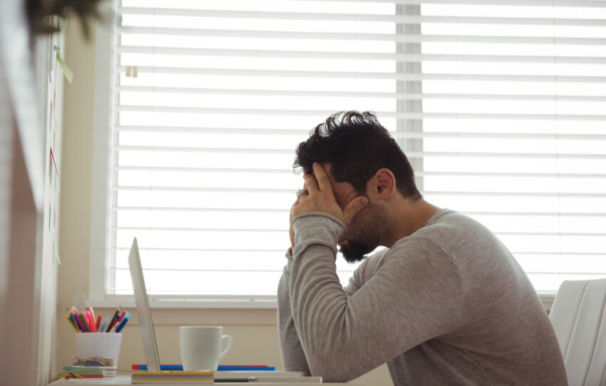 homem estressado sentado com as mãos na cabeça